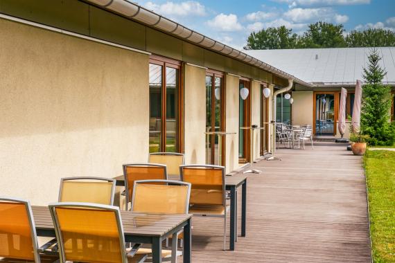 Man sieht den Außenbreich des Seminargebäudes mit Tischen und Stühlrn.