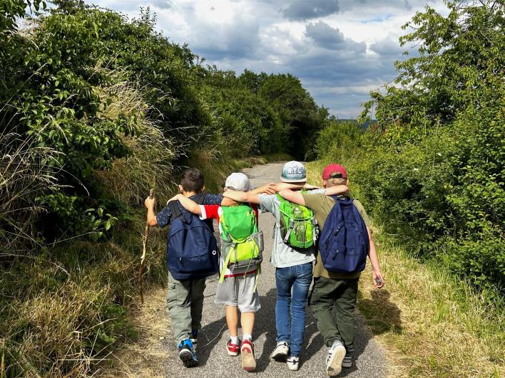 Man sieht vier Freunde, welche Arm in Arm wandern.