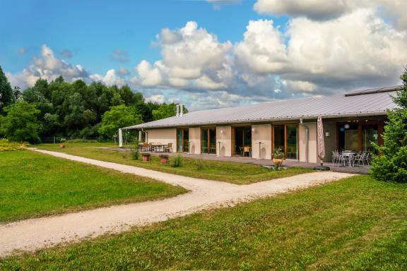Man sieht das Seminargebäude von außen im Sommer mit grünem Gras und blauem Himmel.