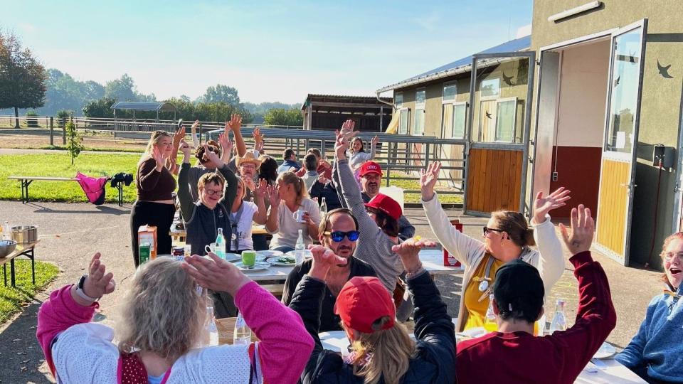 Das Bild zeigt eine jubelnde Menschengruppe auf Gut Aufeld